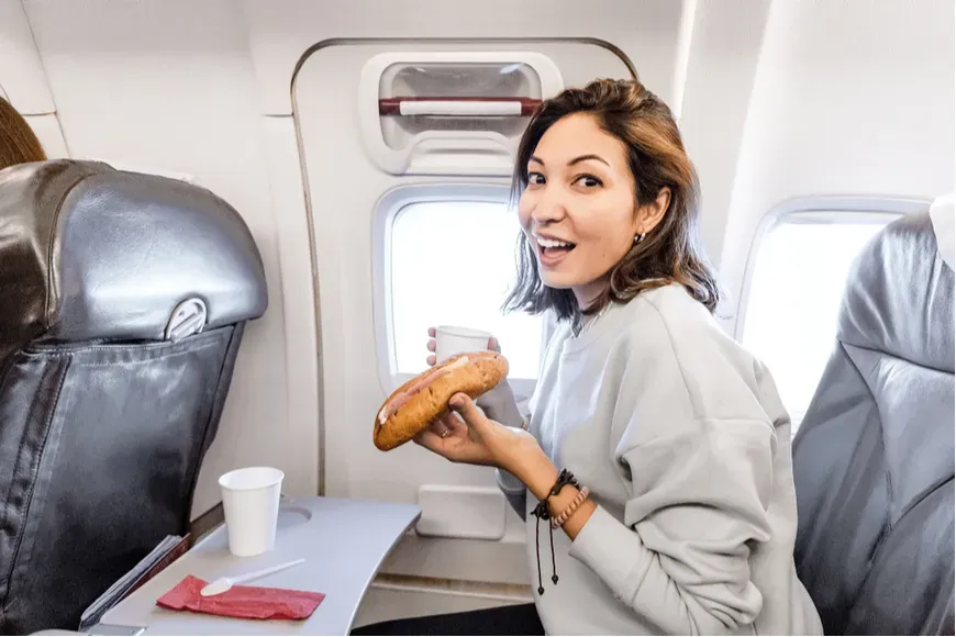 woman eating sandwich on plane.